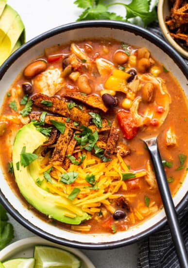 A Slow Cooker Chicken Tortilla Soup served with tortilla chips and guacamole.