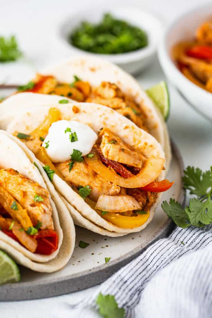 Chicken tacos with peppers and sour cream on a plate.