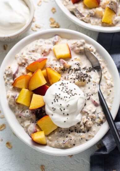 A bowl of oatmeal with peaches and yoghurt.