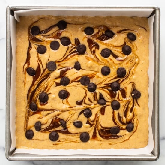 A brownie with chocolate chips and caramel sauce in a baking pan.