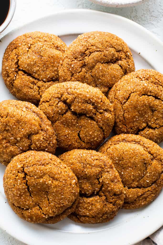 Ginger cookies on a plate next to a cup of coffee.