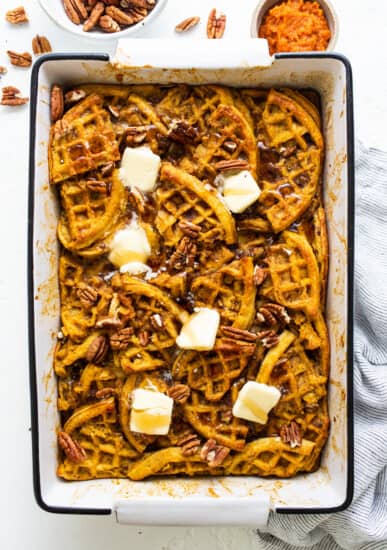 Pumpkin waffles in a baking dish with butter and pecans.