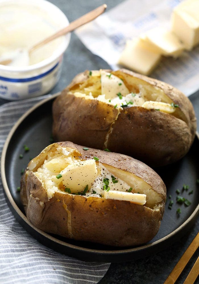 crock pot baked potatoes on a plate topped with butter