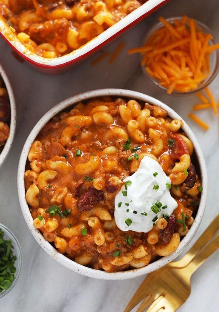 Two bowls of chili mac and cheese topped with sour cream.