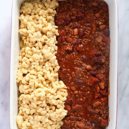 a casserole dish with chili, macaroni and cheese.