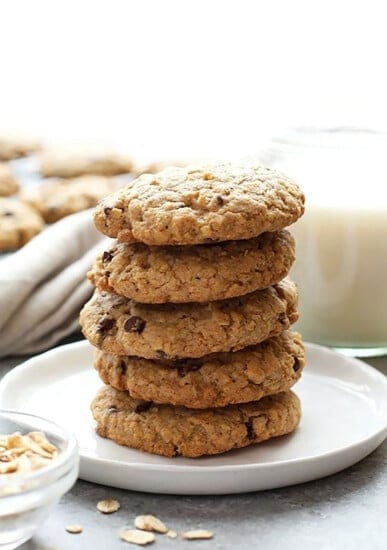 Healthy stack of oatmeal cookies on a plate next to a glass of milk.