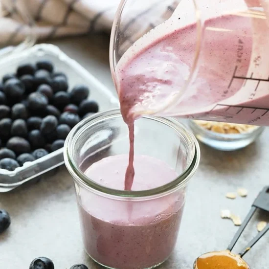 a person pouring a Peanut Butter and Jelly Protein Smoothie.