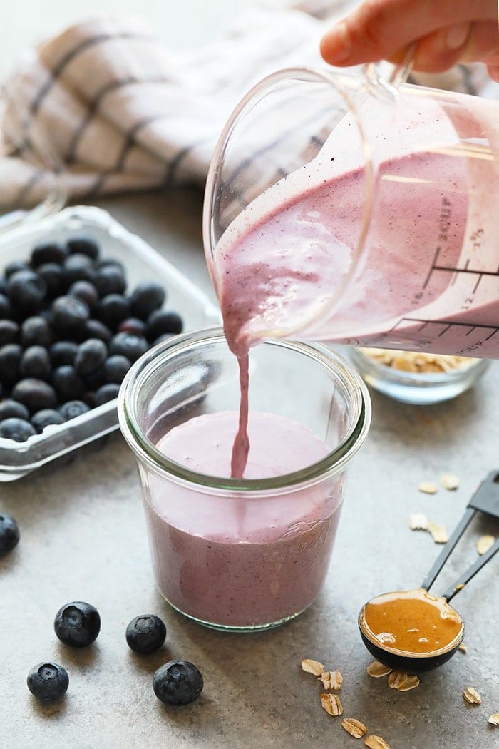 pouring smoothie into glass.