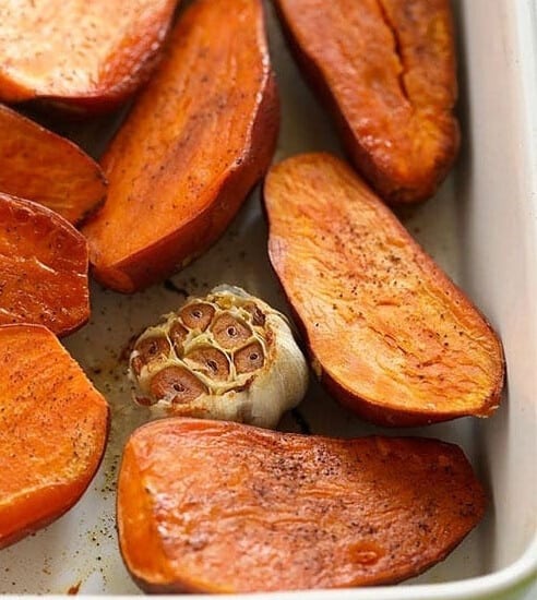 Roasted sweet potatoes in a green baking dish.